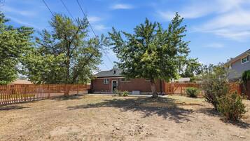 A residential property with a brick house, fenced yard, and mature trees.