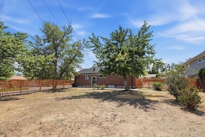 A residential property with a brick house, fenced yard, and mature trees.