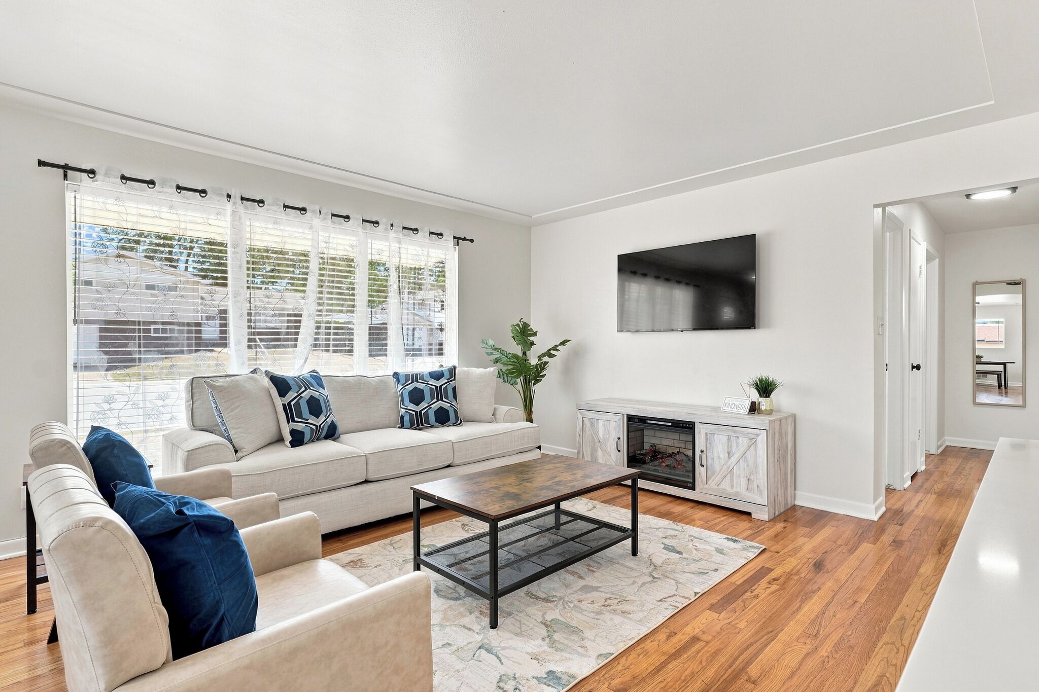 A modern living room with a sofa, coffee table, fireplace, and a TV mounted on the wall.