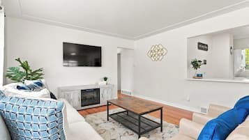 A modern living room with a fireplace, a flat-screen TV, and a comfortable seating area.