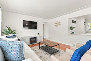 A modern living room with a fireplace, a flat-screen TV, and a comfortable seating area.