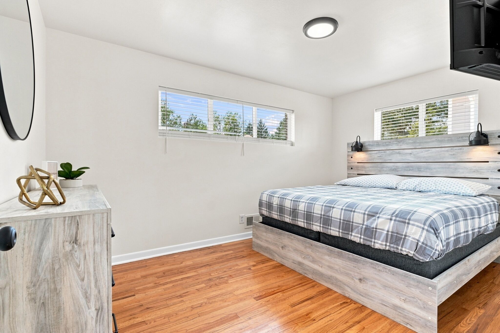 A bedroom with a bed, a window, a bedside table, and a wall-mounted shelf.
