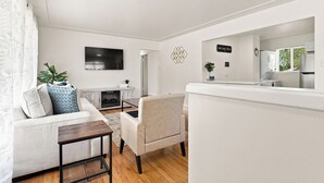 A modern living room with a sofa, armchair, and a flat-screen TV mounted on the wall.