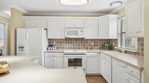 A kitchen with white cabinets, a microwave, a stove, and a sink. - Coucher du Soleil at Seascape, 3 bedroom Condo Miramar Beach Florida (Miramar Beach)