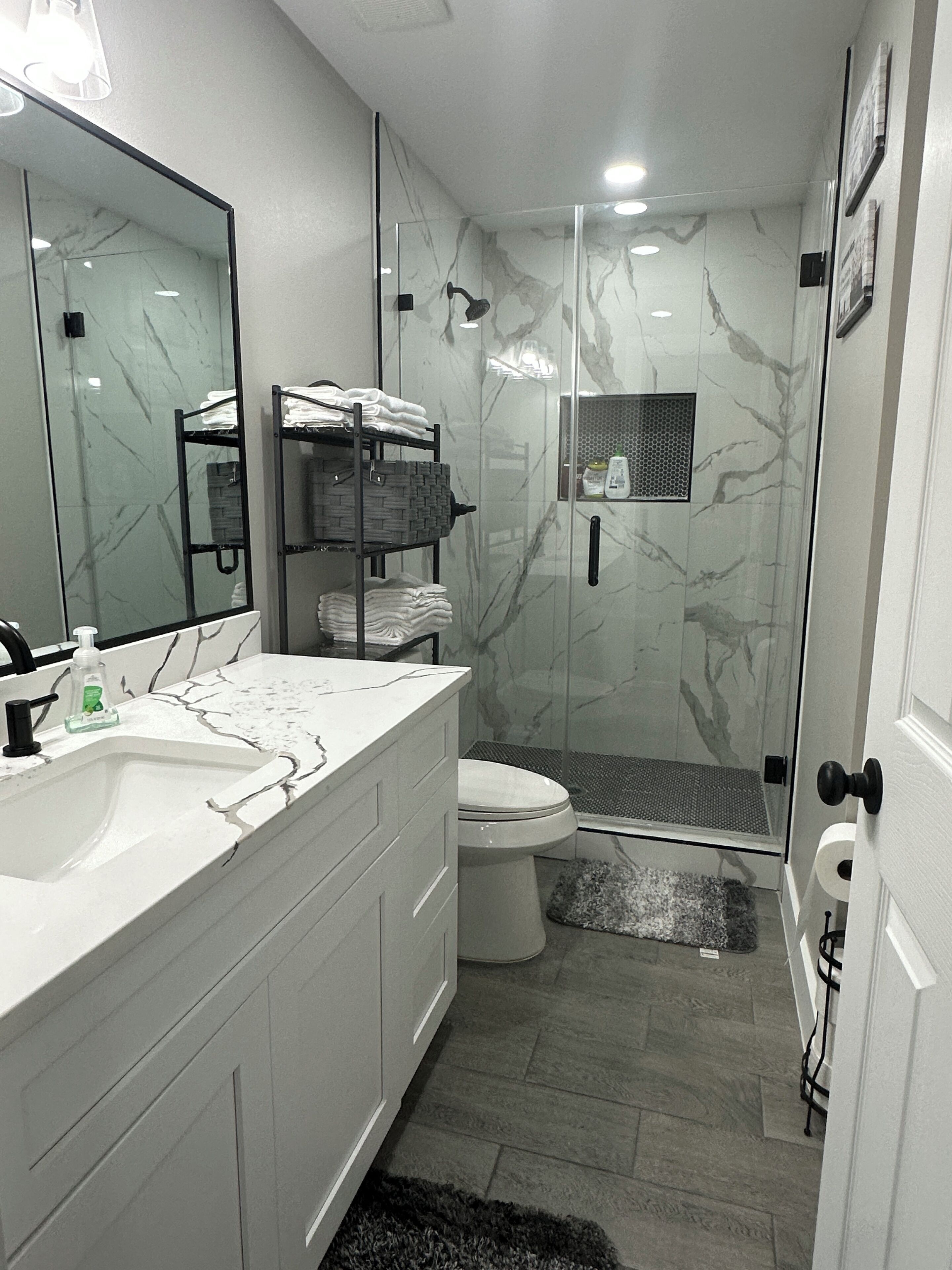 A modern bathroom with a glass shower enclosure, a white sink, and a toilet.