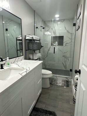Un bagno moderno con cabina doccia in vetro, lavandino bianco e water.