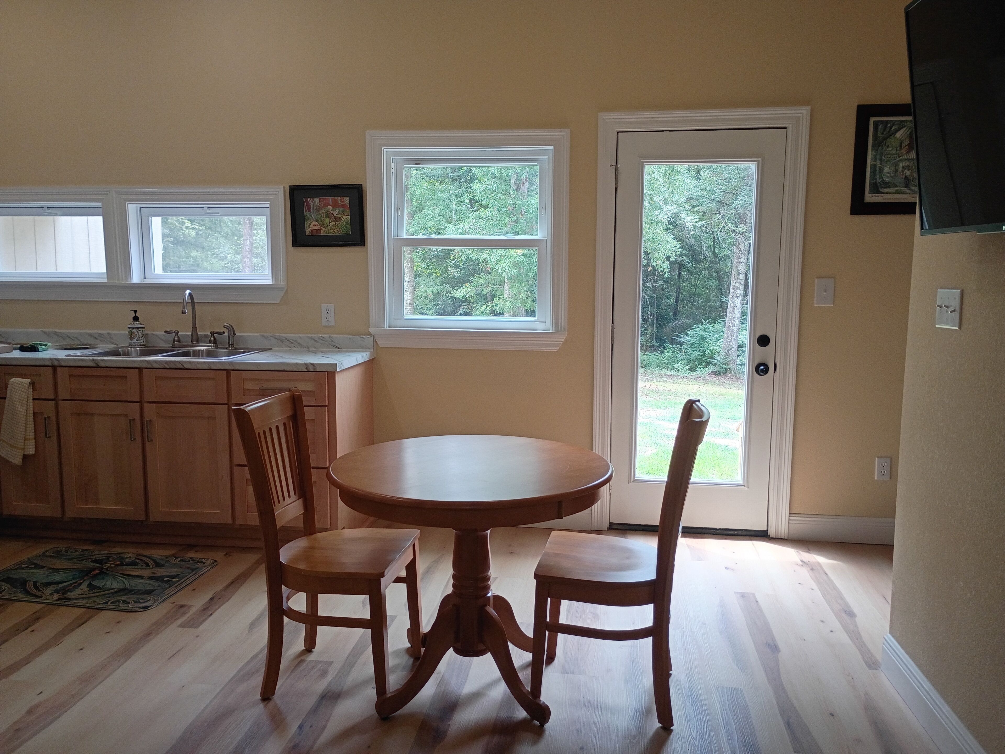 A kitchen with a dining table and chairs, a window, and a door leading outside.