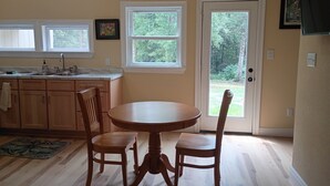 A kitchen with a dining table and chairs, a window, and a door leading outside. - Private Woodland Cottage—Secluded Yet 5 Minutes from Town (Poplarville)