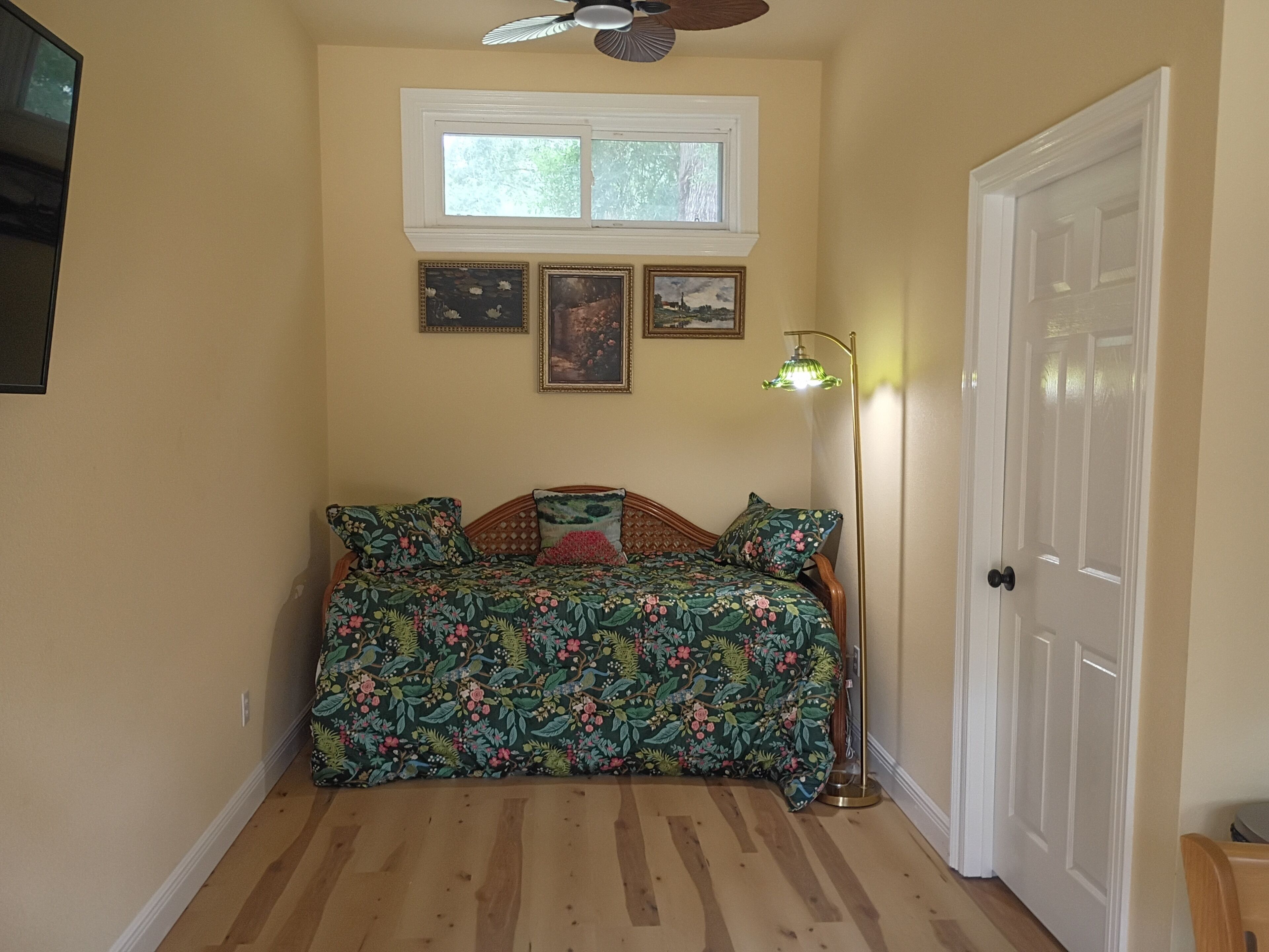 A room with a bed, a window, a door, and a ceiling fan.