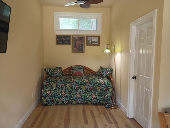 A room with a bed, a window, a door, and a ceiling fan.