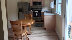 A compact kitchen with wooden cabinets, a stainless steel refrigerator, an oven, and a sink. - Private Woodland Cottage—Secluded Yet 5 Minutes from Town (Poplarville)