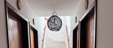 A staircase with wooden doors on either side, leading to a landing with a hanging light fixture.