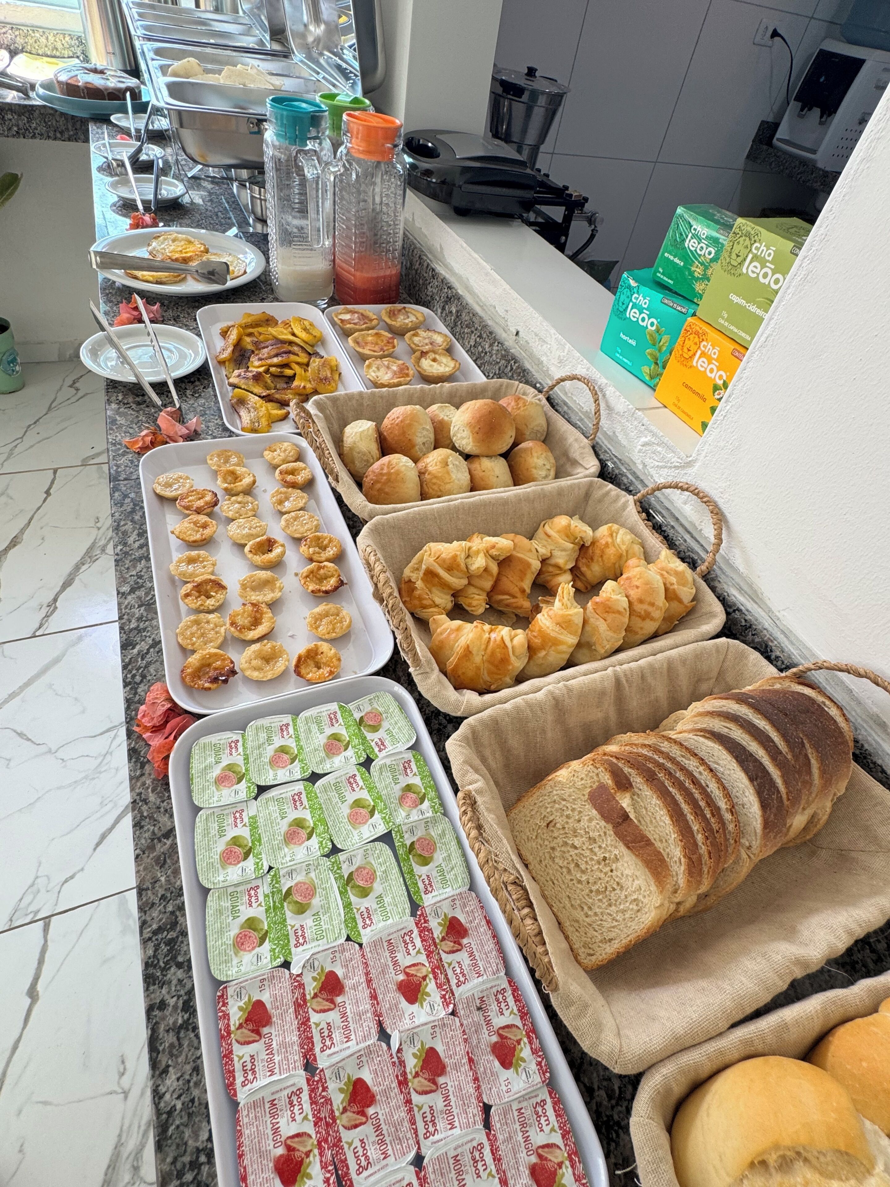 Un bufé con diversas opciones de comida, incluyendo pasteles, pan y bocadillos envasados.