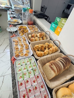 A buffet with various food items including pastries, bread, and packaged snacks. - Pousada Vila Mar Japaratinga (Japaratinga)