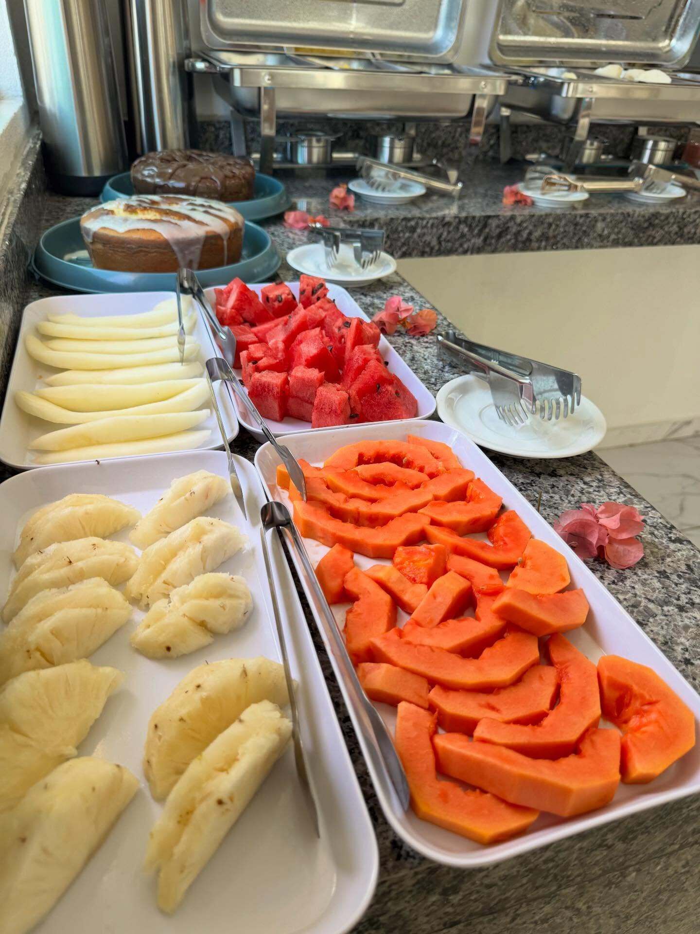 A buffet with various food items including bananas, watermelon, and sweet potatoes.
