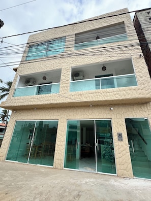 A multi-story building with large glass windows and balconies. - Pousada Vila Mar Japaratinga (Japaratinga)