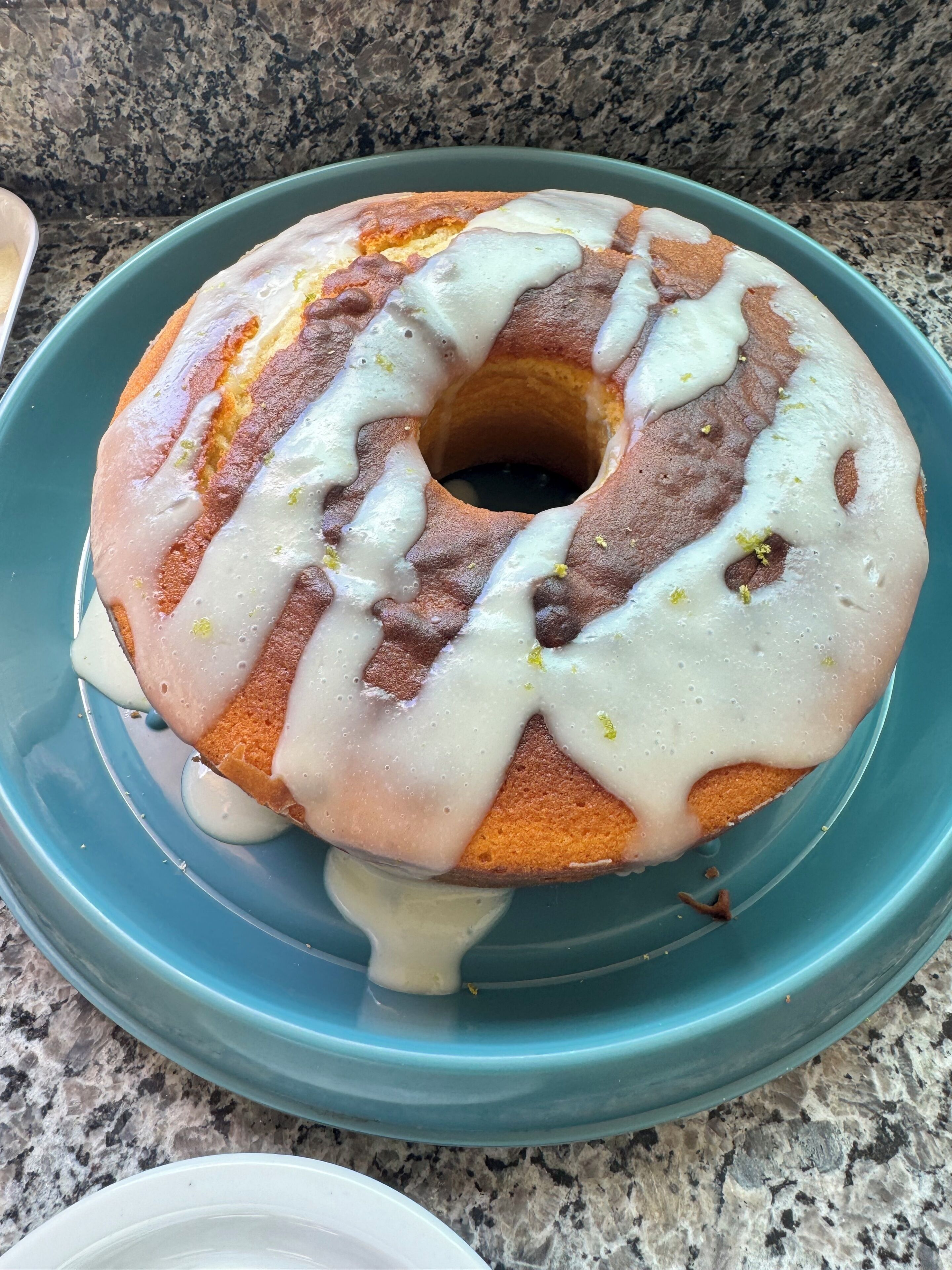 Un pastel redondo con glaseado blanco sobre un plato azul.
