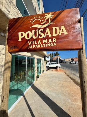 A wooden sign with 'POUSADA' and 'VILA MAR JAPARATINGA' indicating a lodging establishment.