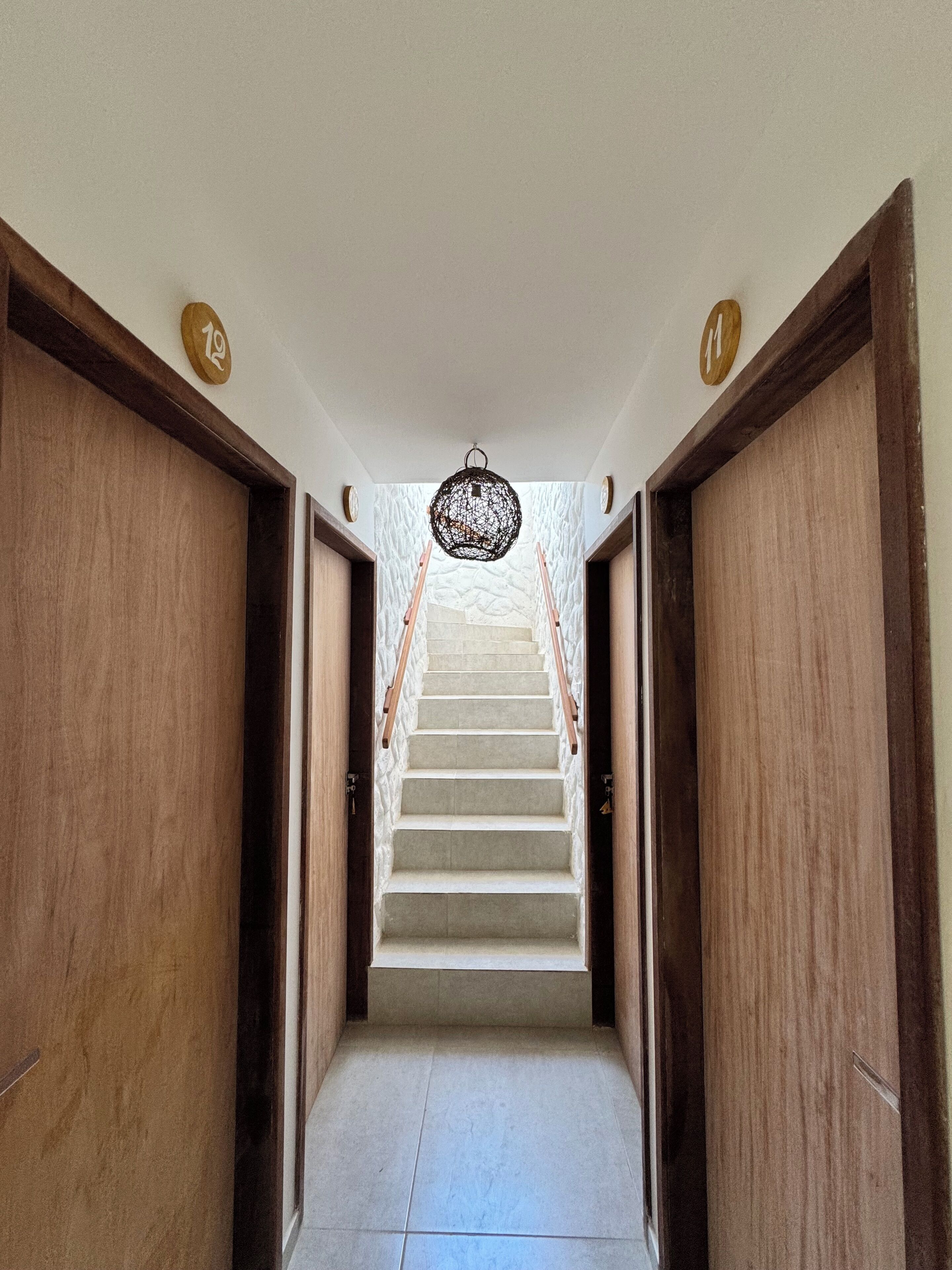 Ein Flur mit Holztüren, einer Treppe und einer hängenden Leuchte.