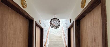 A hallway with wooden doors, a staircase, and a hanging light fixture.