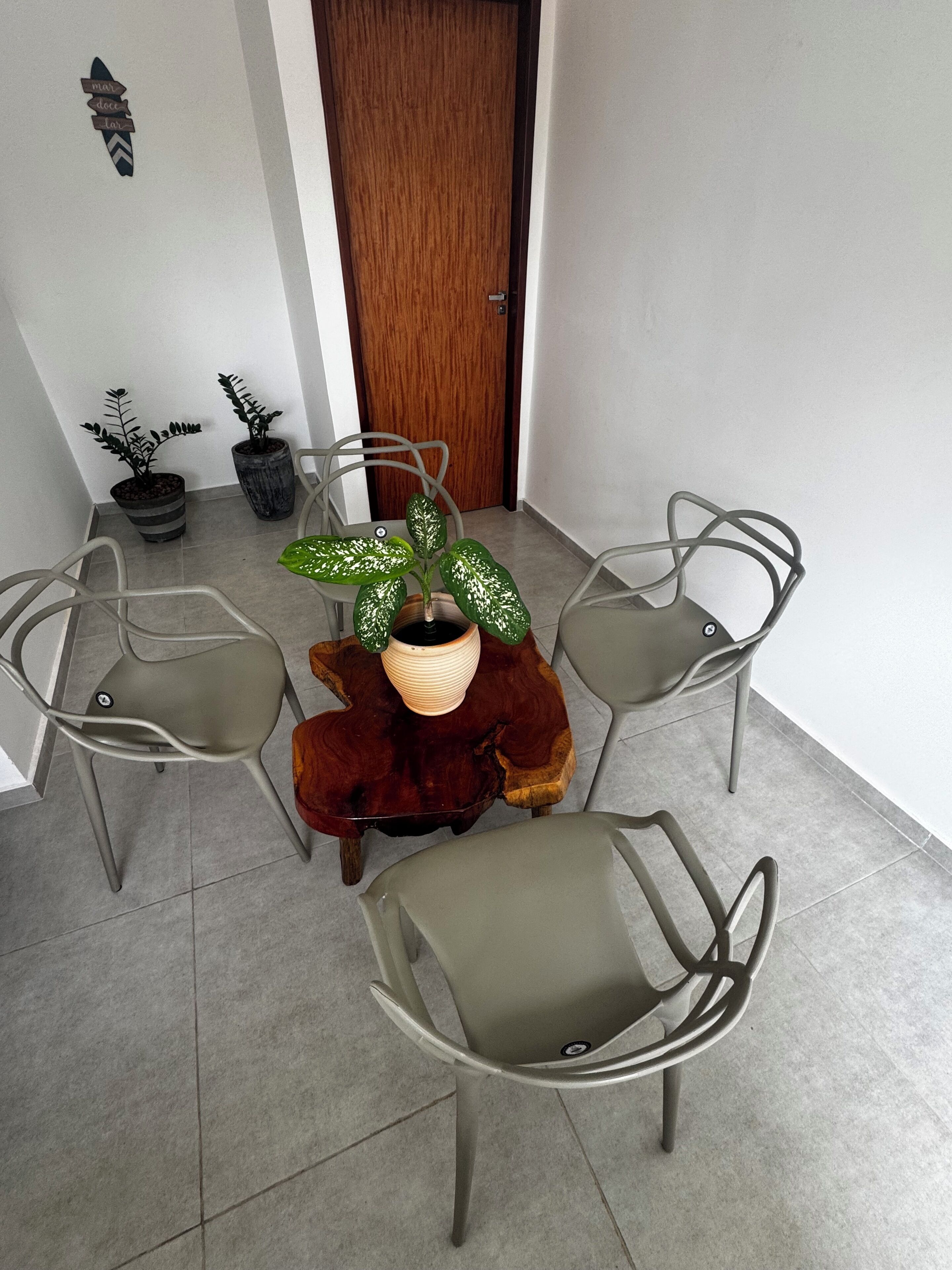 A dining area with a round table and four chairs, a potted plant, and a wooden door in the background.