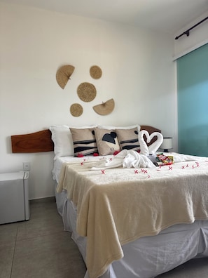 A neatly made bed with a beige blanket, white pillows, and a heart-shaped pillow.