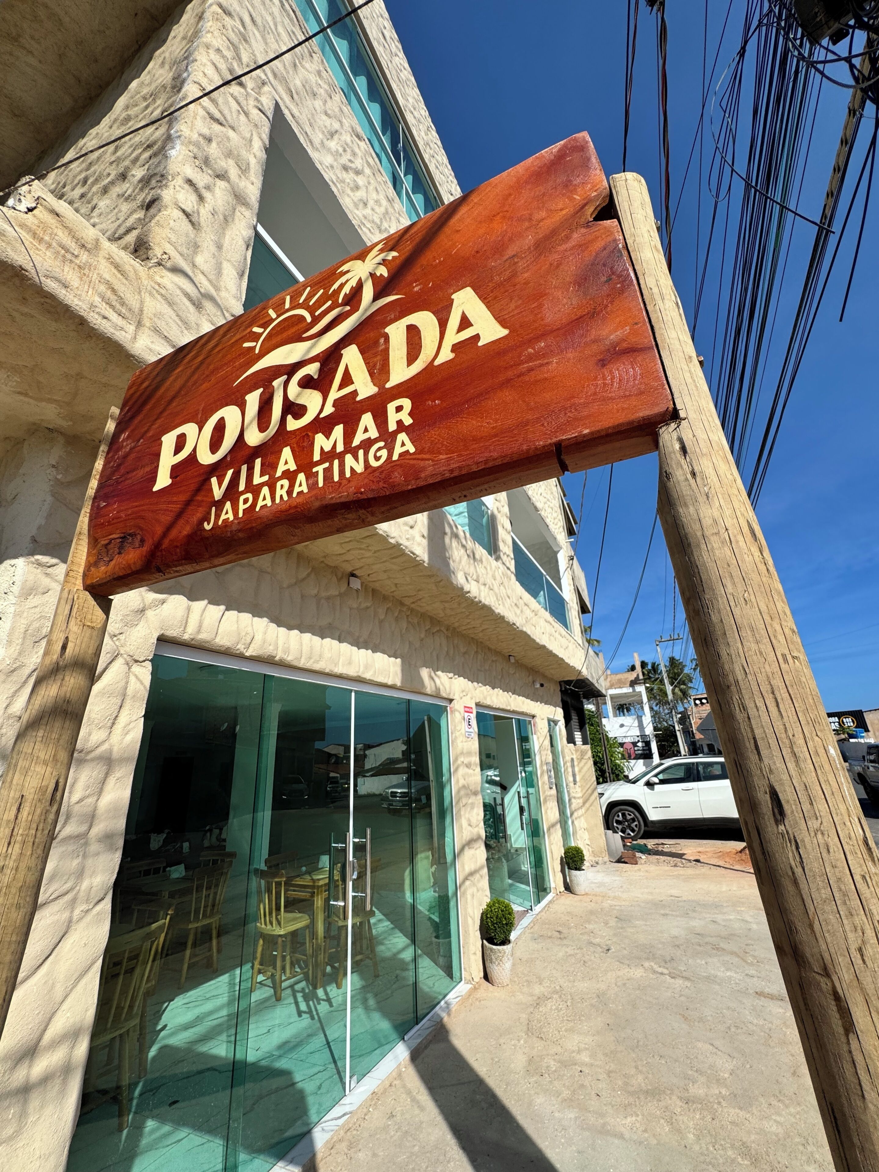 A wooden sign with 'POUSADA' and 'VILA MAR JAPARATANGA' written on it, indicating a hotel or guesthouse.