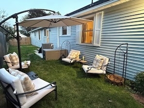A backyard with a patio area featuring outdoor furniture and a large umbrella.