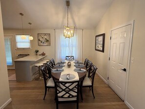 A dining area with a round table, chairs, a chandelier, and artwork on the walls.