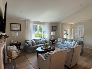 A spacious living room with two sofas, a coffee table, and a television mounted on the wall.