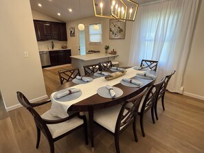 A dining area with a wooden table set for six, surrounded by chairs, in a modern kitchen and dining space.