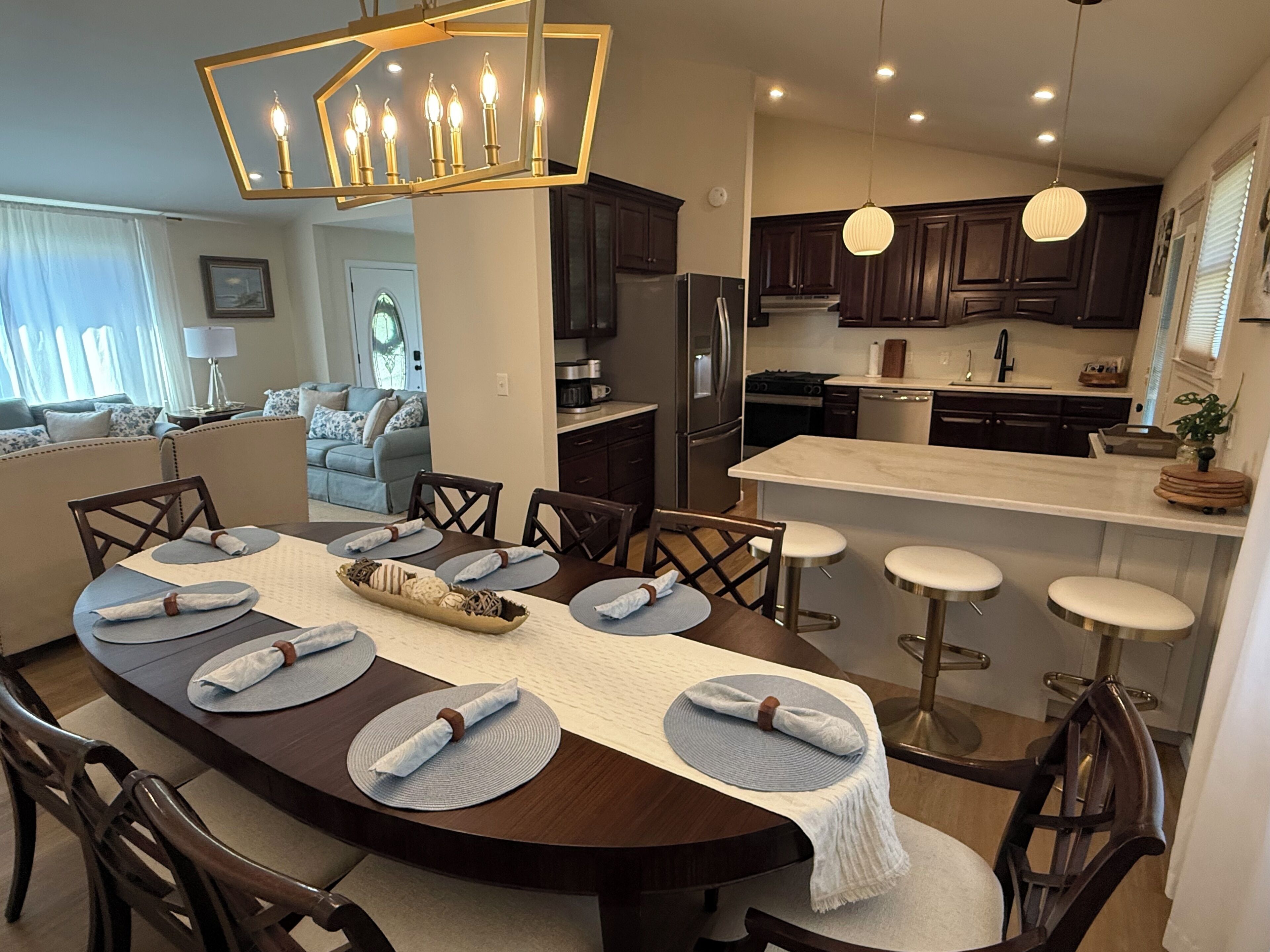 A modern kitchen with dark wood cabinets, stainless steel appliances, and a central island with stools.