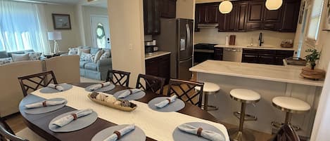A modern kitchen with dark wood cabinets, stainless steel appliances, and a central island with stools.
