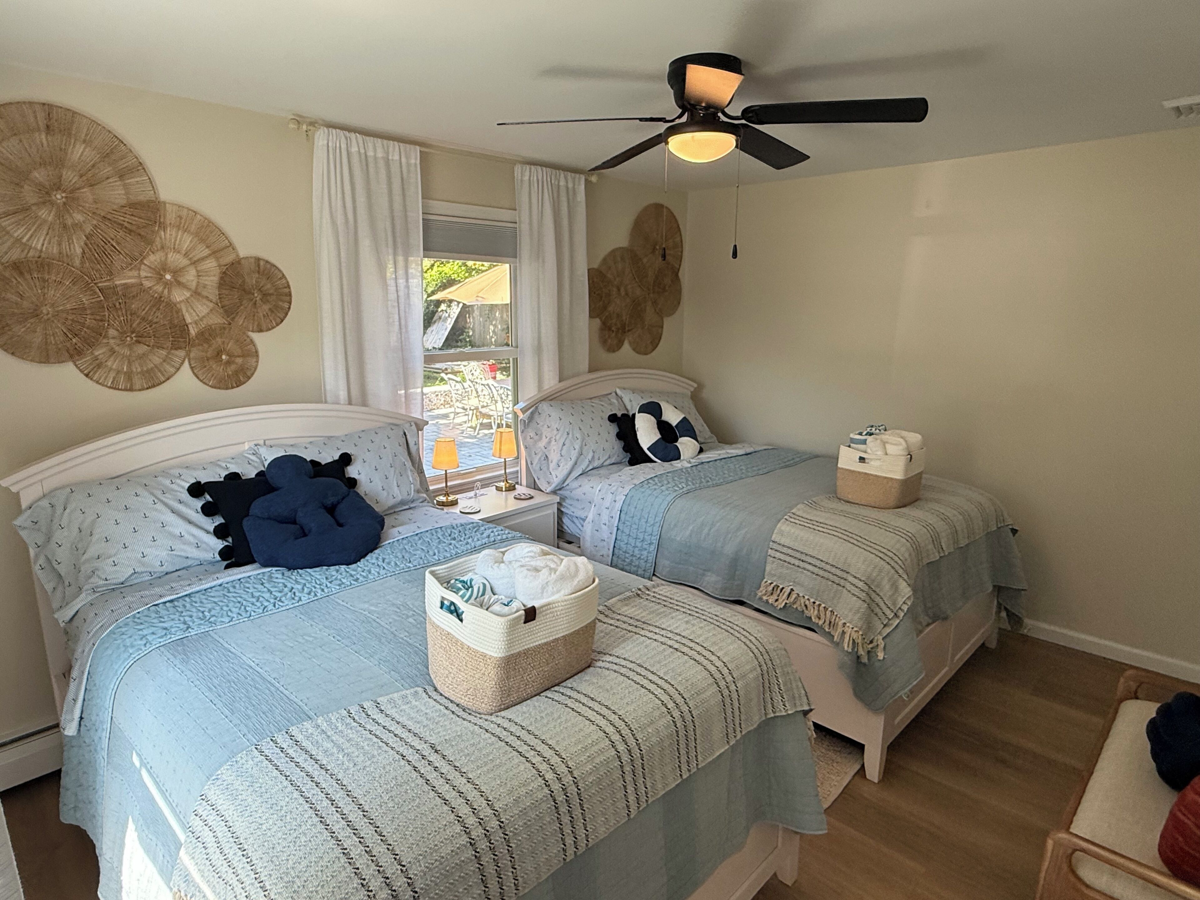 Ein Schlafzimmer mit zwei Betten, einem Deckenventilator und einem Fenster mit Vorhängen.