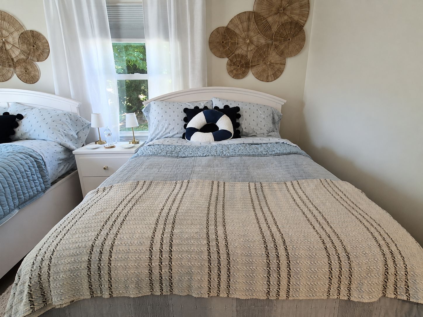 Un lit double avec une couvre-lit à motifs, une table de chevet avec une lampe et des œuvres d’art décoratives accrochées au mur.