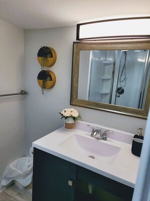 Een badkamer met een wit wastafel, een spiegel en een handdoekhouder.