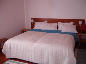 A standard hotel room with a single bed, a nightstand, a lamp, and a small table.