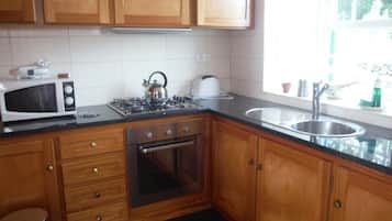 Una cocina con armarios de madera, un microondas, una estufa a gas y un lavabo.