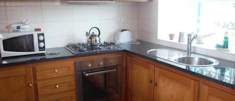 A kitchen with wooden cabinets, a microwave, a gas stove, and a sink.