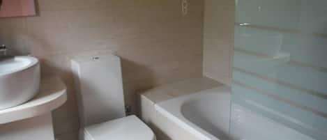 Egy fürdőszoba, amelyben WC, mosdókagyló és fürdőkád található.