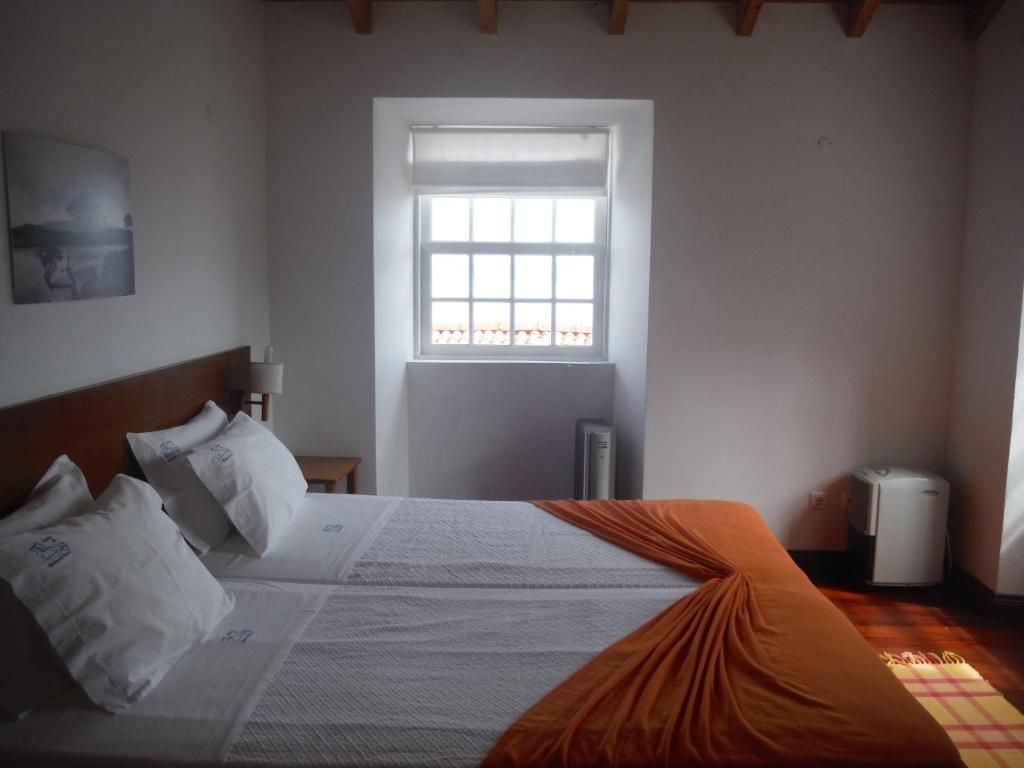 Ein Schlafzimmer mit einem Bett, einem Fenster, einer Heizung und einem Wandbild.