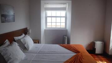 Ein Schlafzimmer mit einem Bett, einem Fenster, einer Heizung und einem Wandbild.