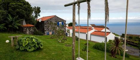 A coastal property with a swing set, a stone house, and a view of the sea.
