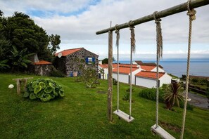 A coastal property with a swing set, a stone house, and a view of the sea.