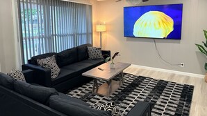 A modern living room with a sofa, a coffee table, and a television mounted on the wall.