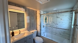 Ein Badezimmer mit Marmorwaschbecken, Toilette und einer Duschkabine.