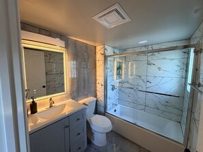 A bathroom with a marble sink, a toilet, and a glass-enclosed shower. - Sweet home, King bed, fenced backyard, and parking (Buffalo)