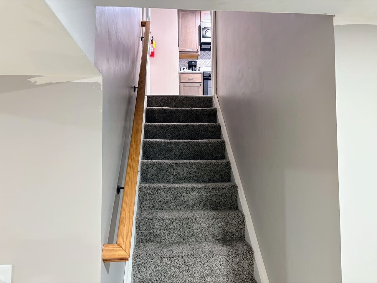 Eine Treppe mit Teppichstufen führt zu einem Küchenbereich.
