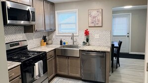 A modern kitchen with a gas stove, stainless steel appliances, and a herringbone tile backsplash.