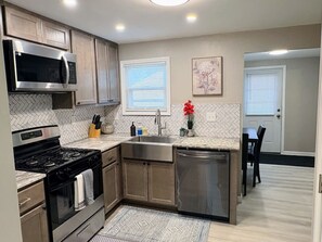 A modern kitchen with a gas stove, stainless steel appliances, and a herringbone tile backsplash.